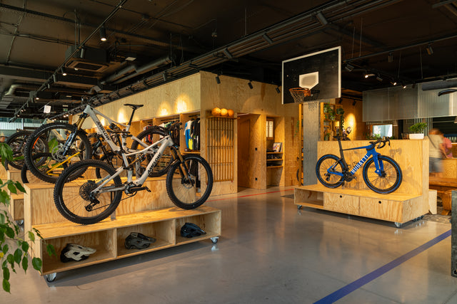 Showroom cyklopredajne Velocity v Bratislave s bicyklami na preglejkových podstavcoch a čiernym technickým stropom s klimatizáciou DAIKIN