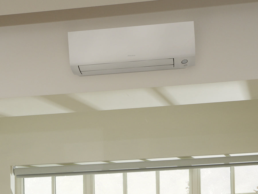 DAIKIN Perfera W Nepura FTXTM30A na stene nad oknom, za ktorým sú zasnežené stromy